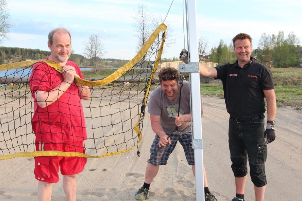 Erling, Håkon og Stian setter opp nettet på volleyballbanen. 